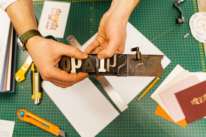Print technician trimming a same-day order on a commercial paper cutter in Seattle