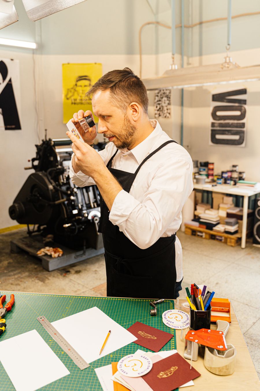 Graphic designer uses magnifying glass to inspect print quality in a design studio.