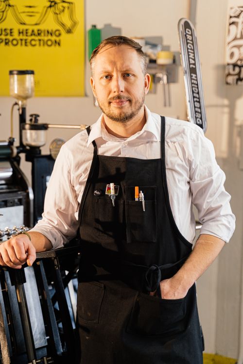Free A focused printmaker in his workshop, wearing an apron, ready for work. Stock Photo