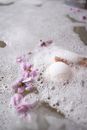 White ball of bath salt on water surface with foam