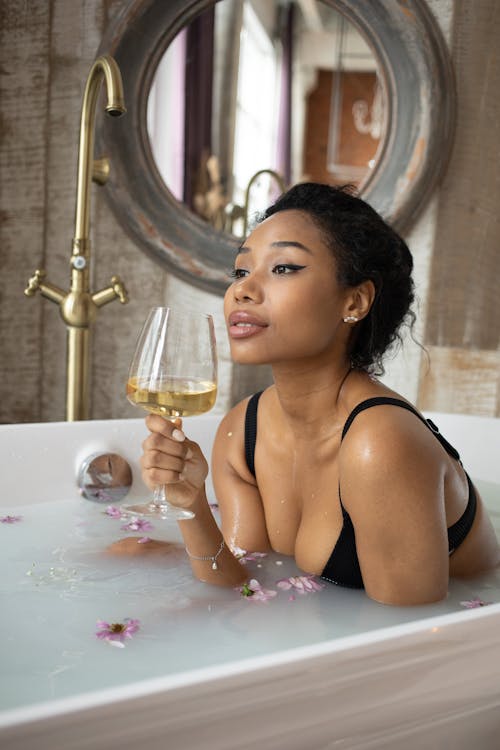 Young ethnic woman in black bra with champagne in hand