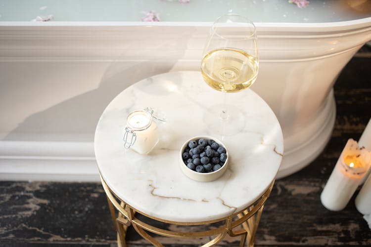 Round Table With Burning Candle Bowl Of Berries And Glass Of Wine