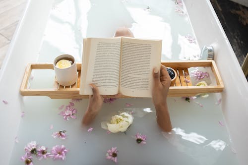 Free Woman reading book while resting in bathtub Stock Photo