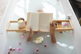 Woman reading book while resting in bathtub