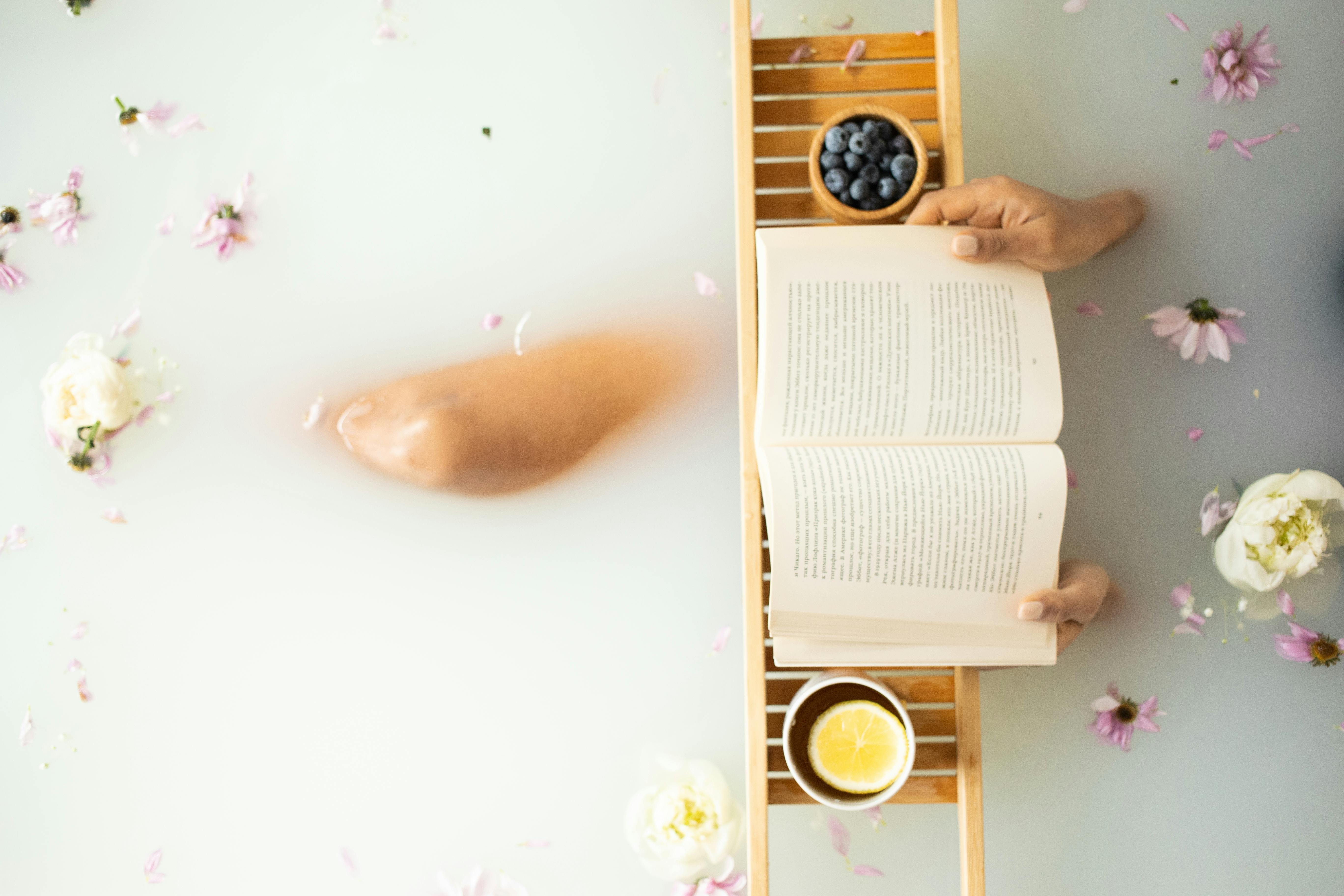 anonymous female in milk bath with flowers reading book