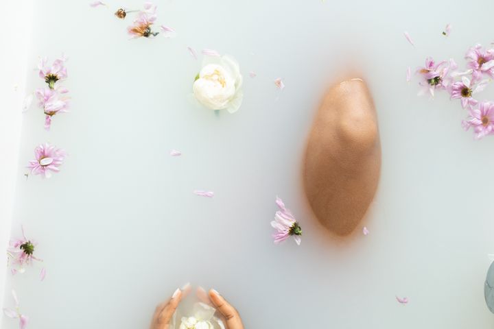 Faceless lady in milk bath with flower petals