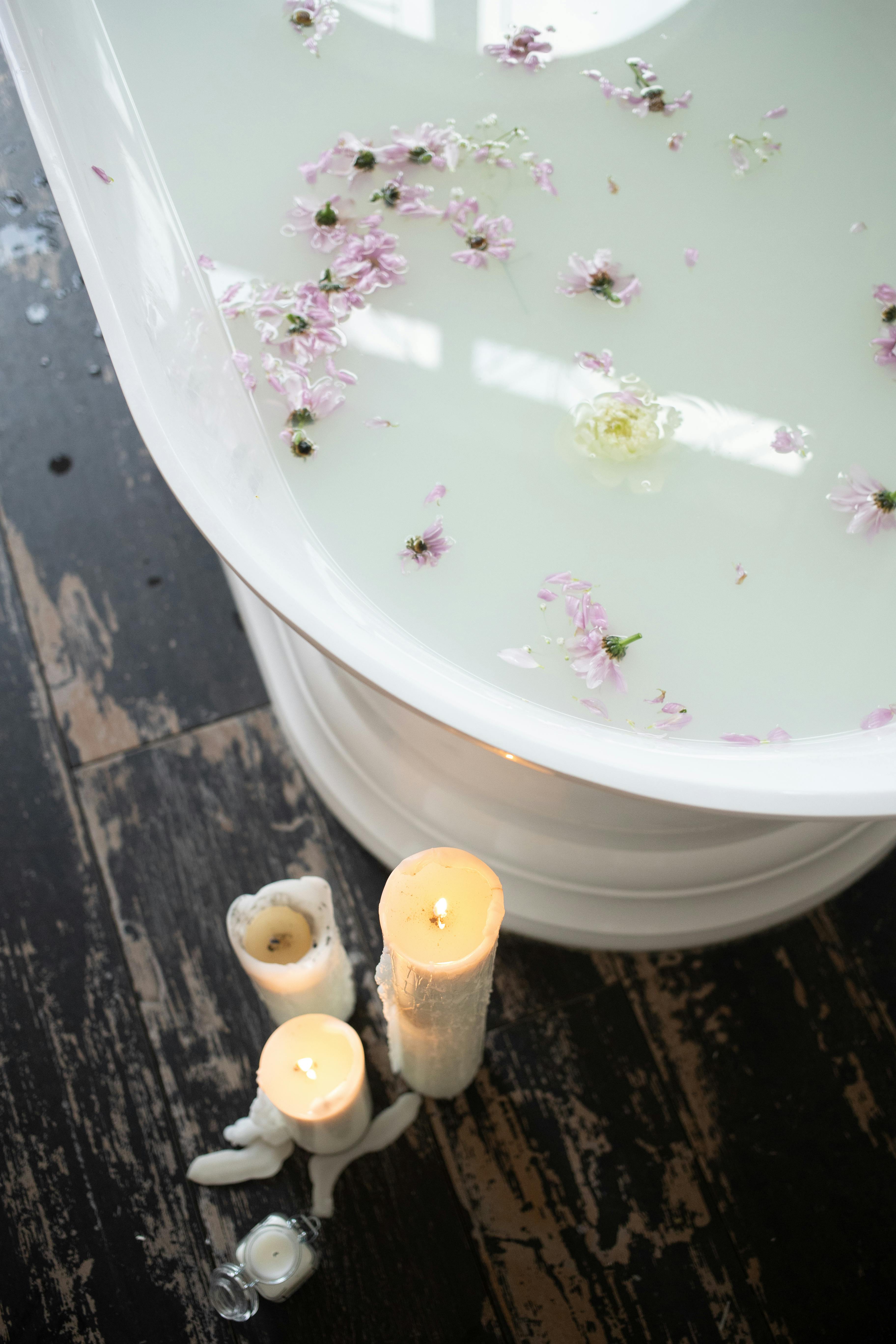 bathroom with candles and white water with flower petals