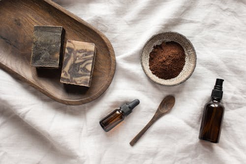 Free Top view of coffee scrub in bowl composed with bottles of aromatic oil on white sheet Stock Photo