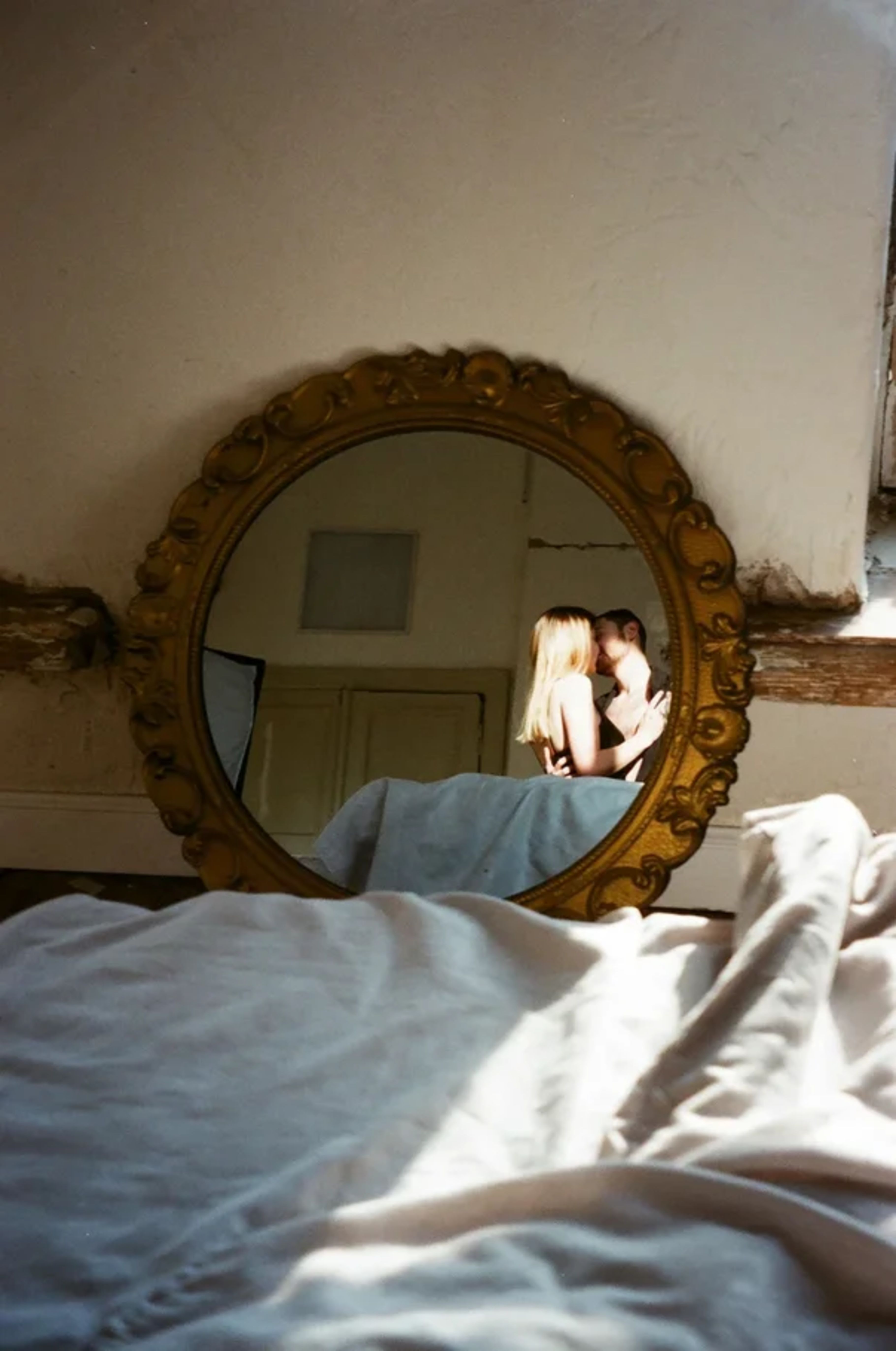 A couple sharing an intimate moment, captured in a mirror's reflection indoors.