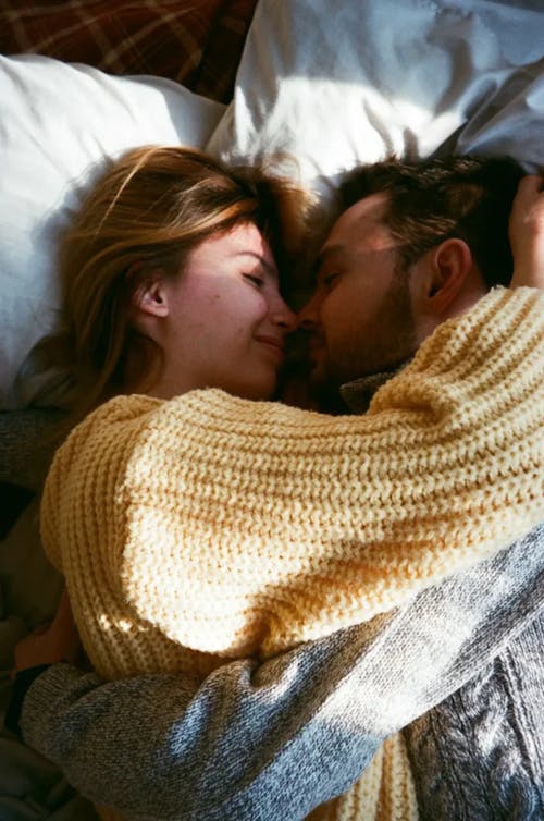 Free Woman in Knit Sweater Lying on Bed with a Man Stock Photo