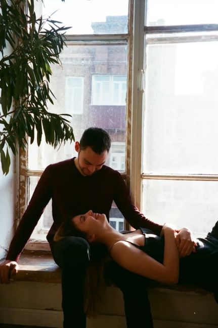 A loving couple enjoys a serene moment by a sunlit window, embracing affectionately.