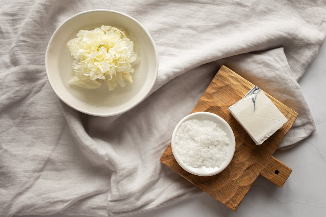 Washcloth in bowl with water near organic scrub and soap