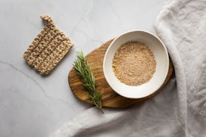 Washcloth composed with organic scrub and branch of rosemary