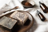 Handmade brown soap on timber board near aromatic oil