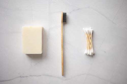 Free From above of bamboo toothbrush placed between organic soap and wooden ear sticks placed on marble table Stock Photo