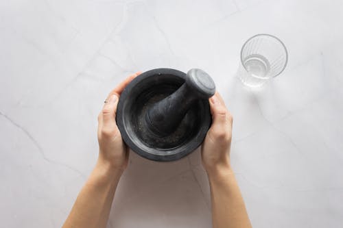 Free Person Place Mortar and Pestle on White Table Stock Photo