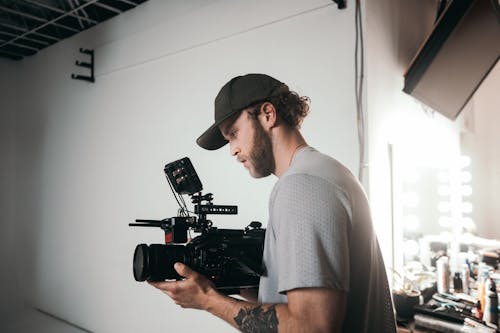 Photograph of a Man with a Cap Holding a Black Camera