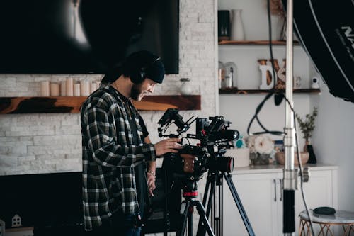 Photo of a Man with a Black Beanie Standing Near a Camera