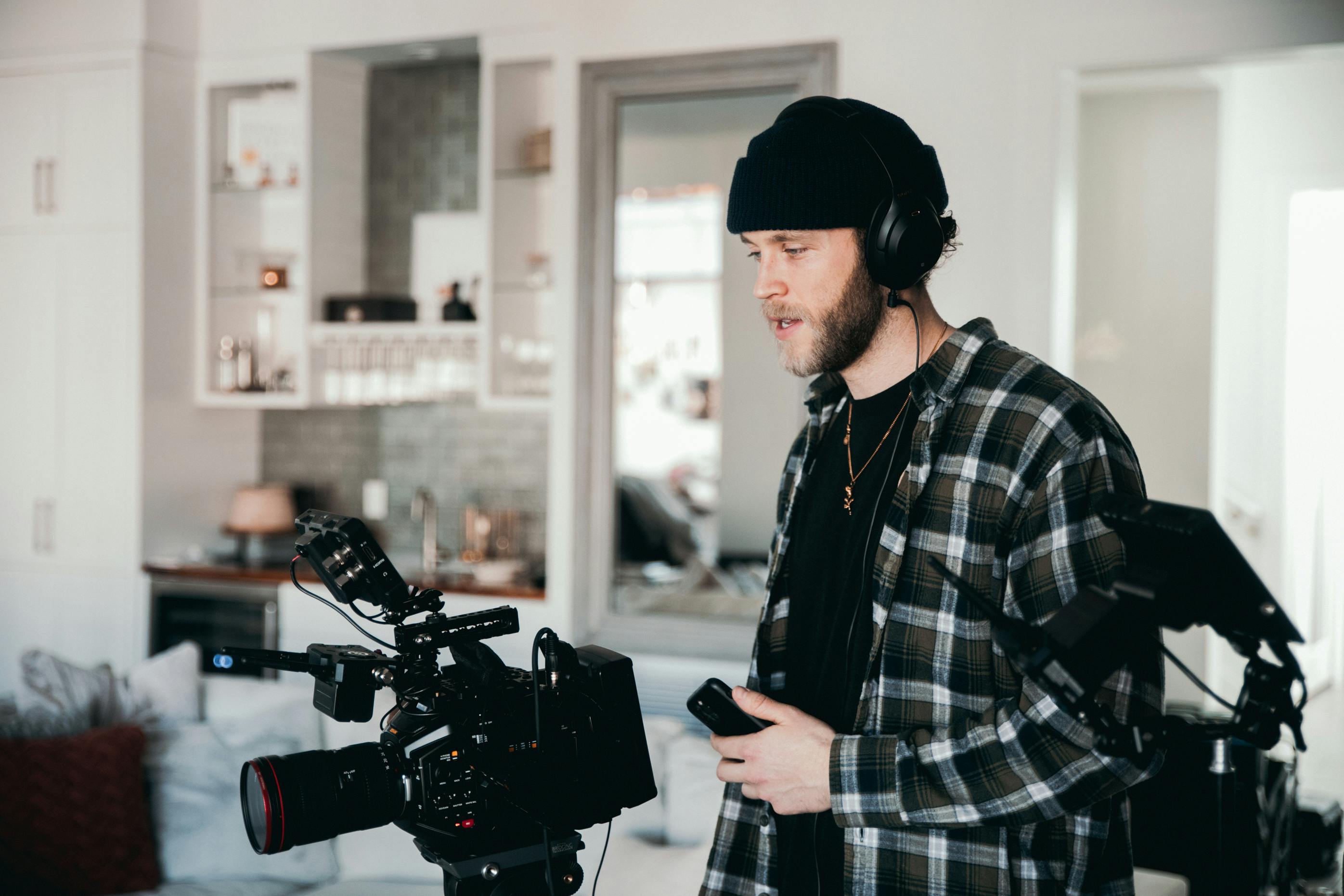 man in black and white plaid dress shirt holding black dslr camera