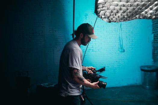 Cinematographer fine-tuning camera settings on a film set with professional lighting.
