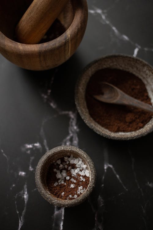 Ceramic bowls with coffee placed near mortar and pestle on table