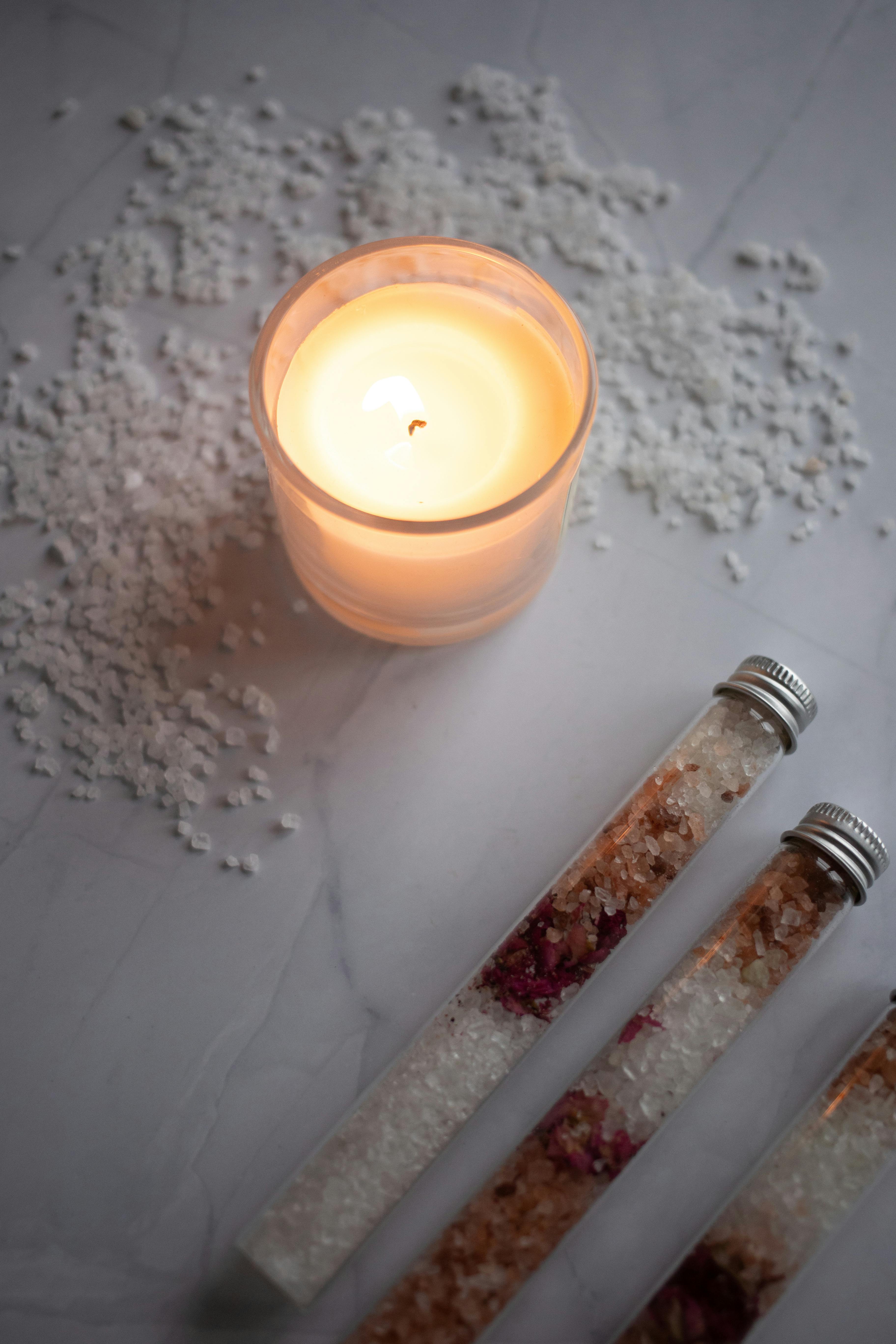 burning candle placed near set of organic salt for bath