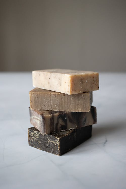 Pile of handmade organic soaps placed in white marble table against blurred background