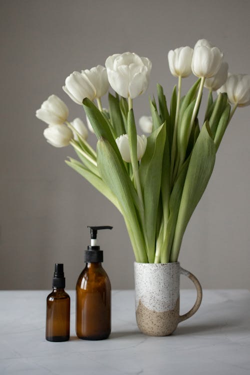 Bouquet of tulips placed near cosmetic products on table