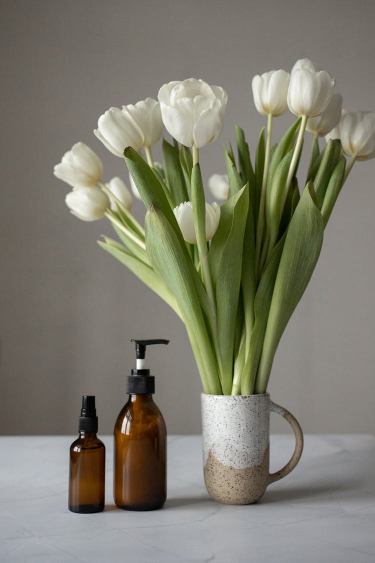 Bouquet Of Tulips Placed Near Cosmetic Products On Table