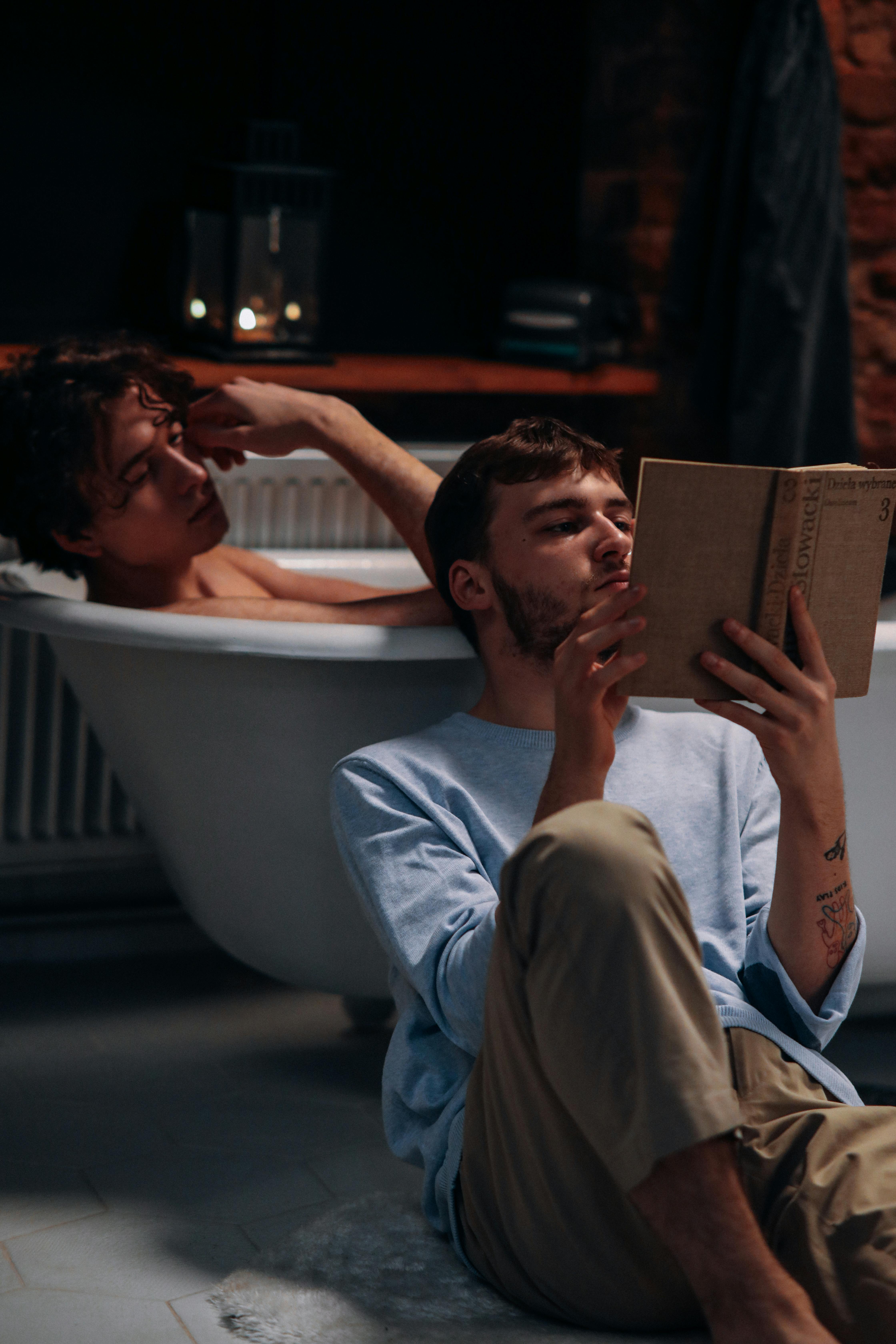 photo of a men reading a book in the bathroom