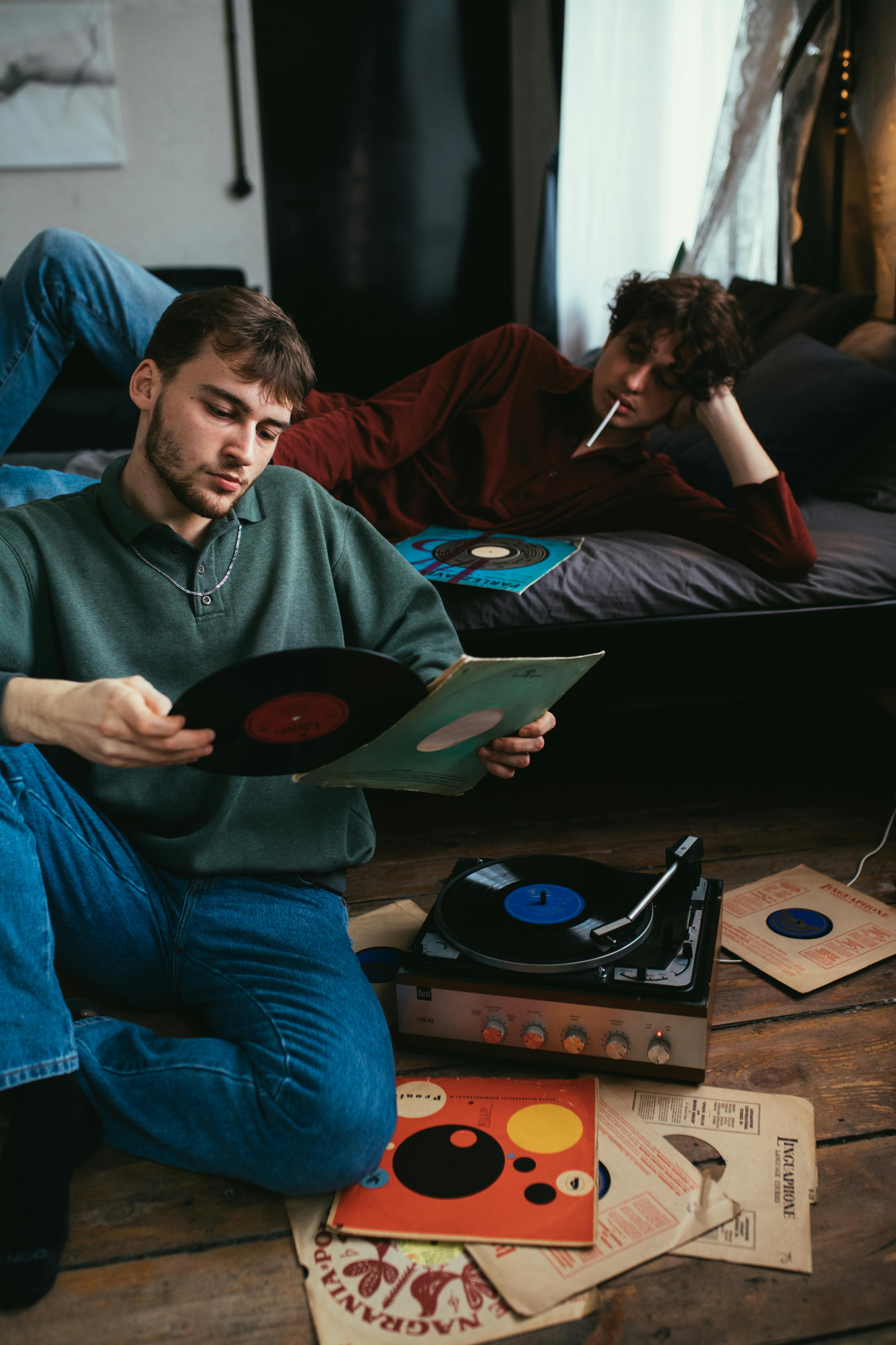 man in gray sweater looking at a vinyl record