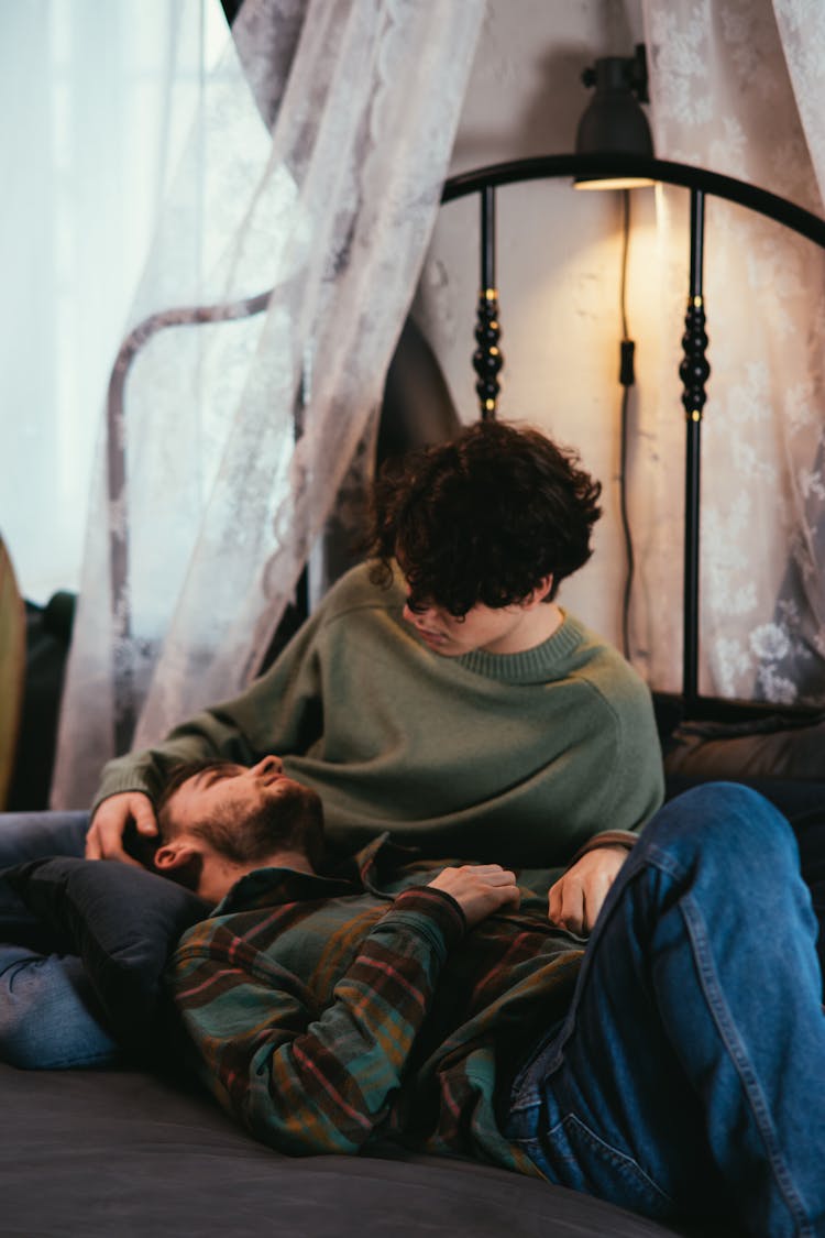 A Couple Looking At Each Other While On The Bed