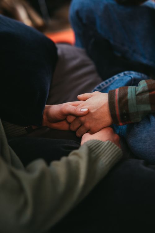 Free Intimate close-up of a couple holding hands, symbolizing love and connection in a cozy setting. Stock Photo