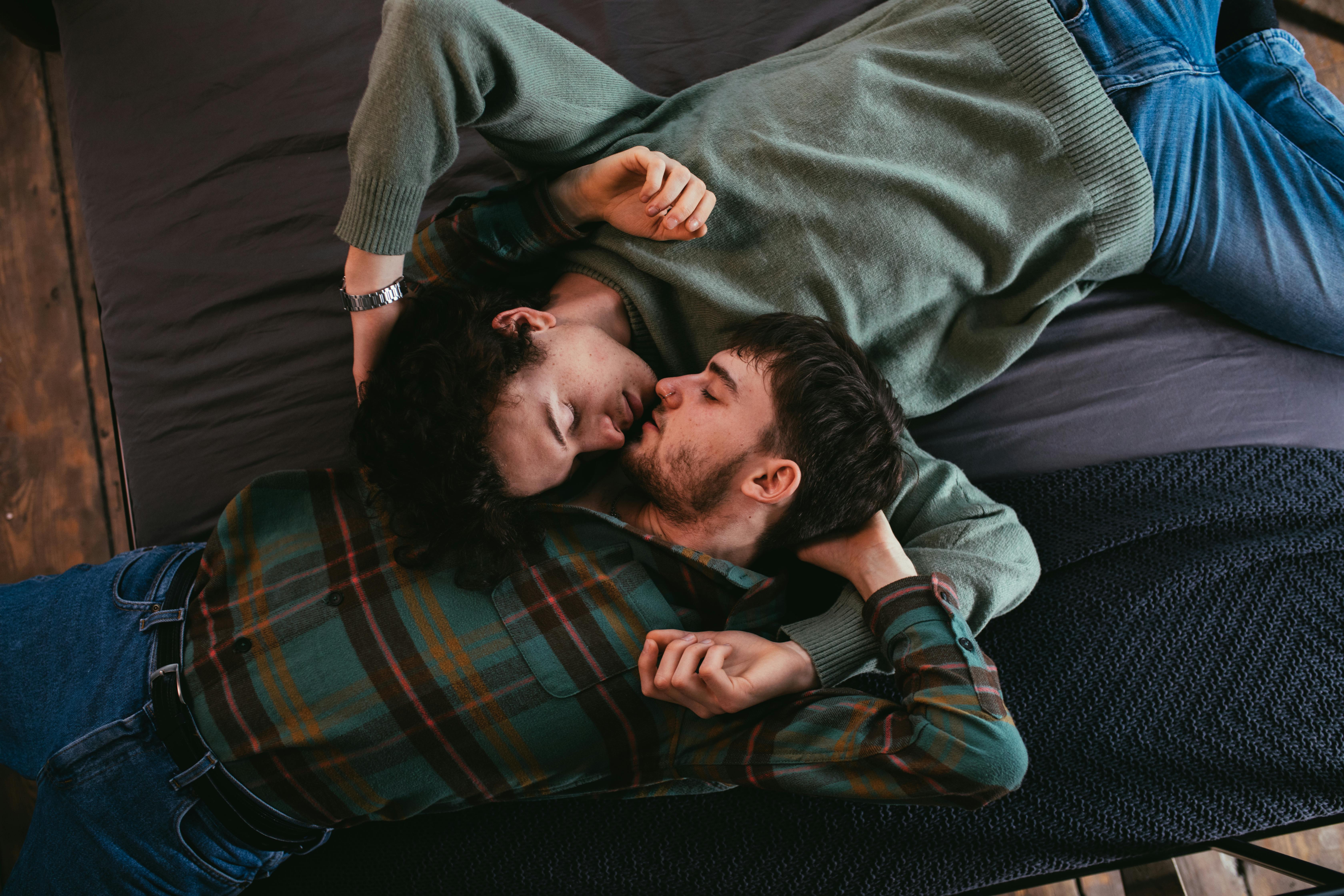 men lying on bed while facing each other