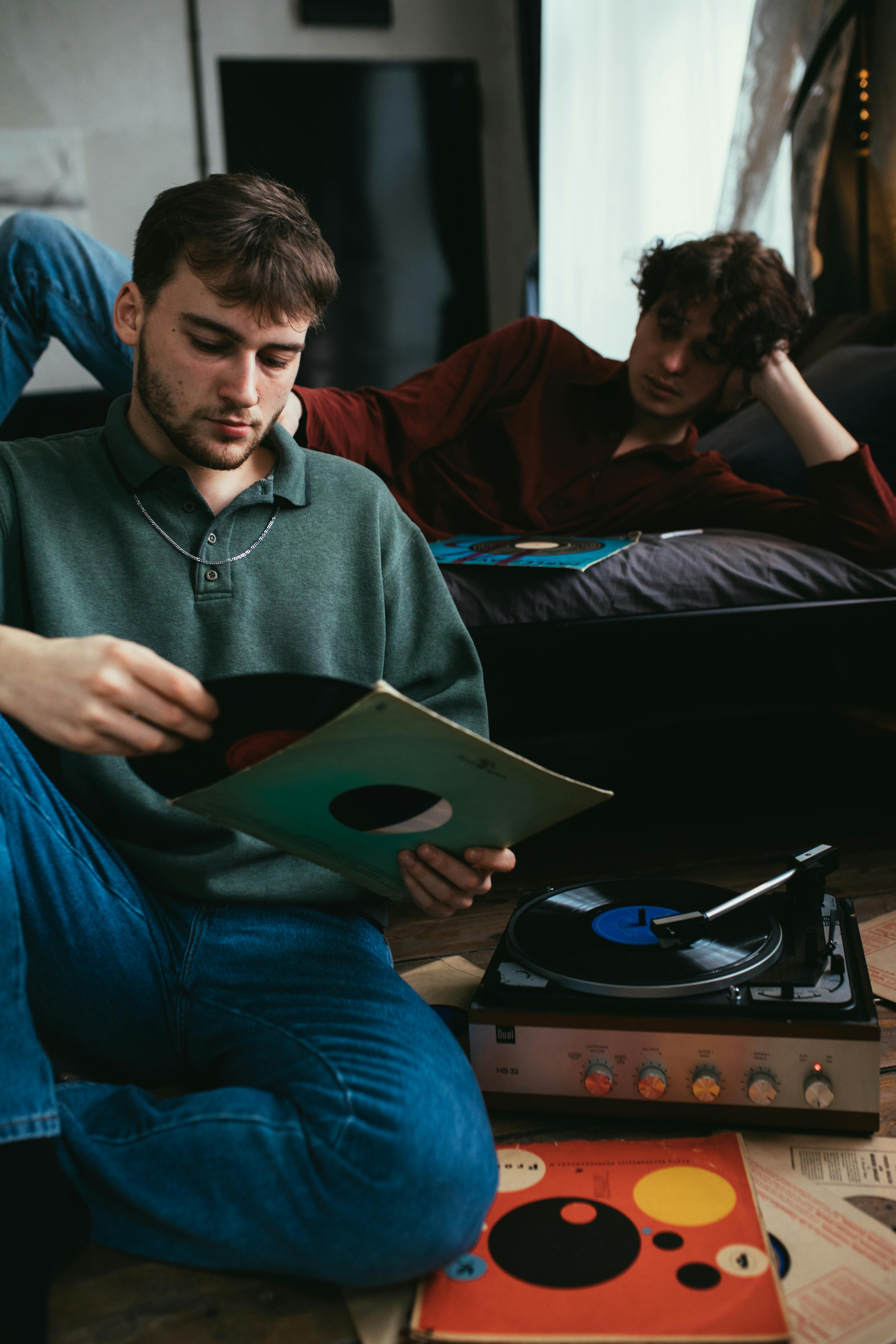 man in gray long sleeve shirt looking at a vinyl record