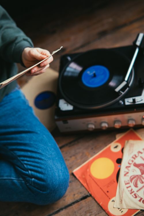 Free A person sits cross-legged enjoying vintage vinyl records on a turntable. Stock Photo