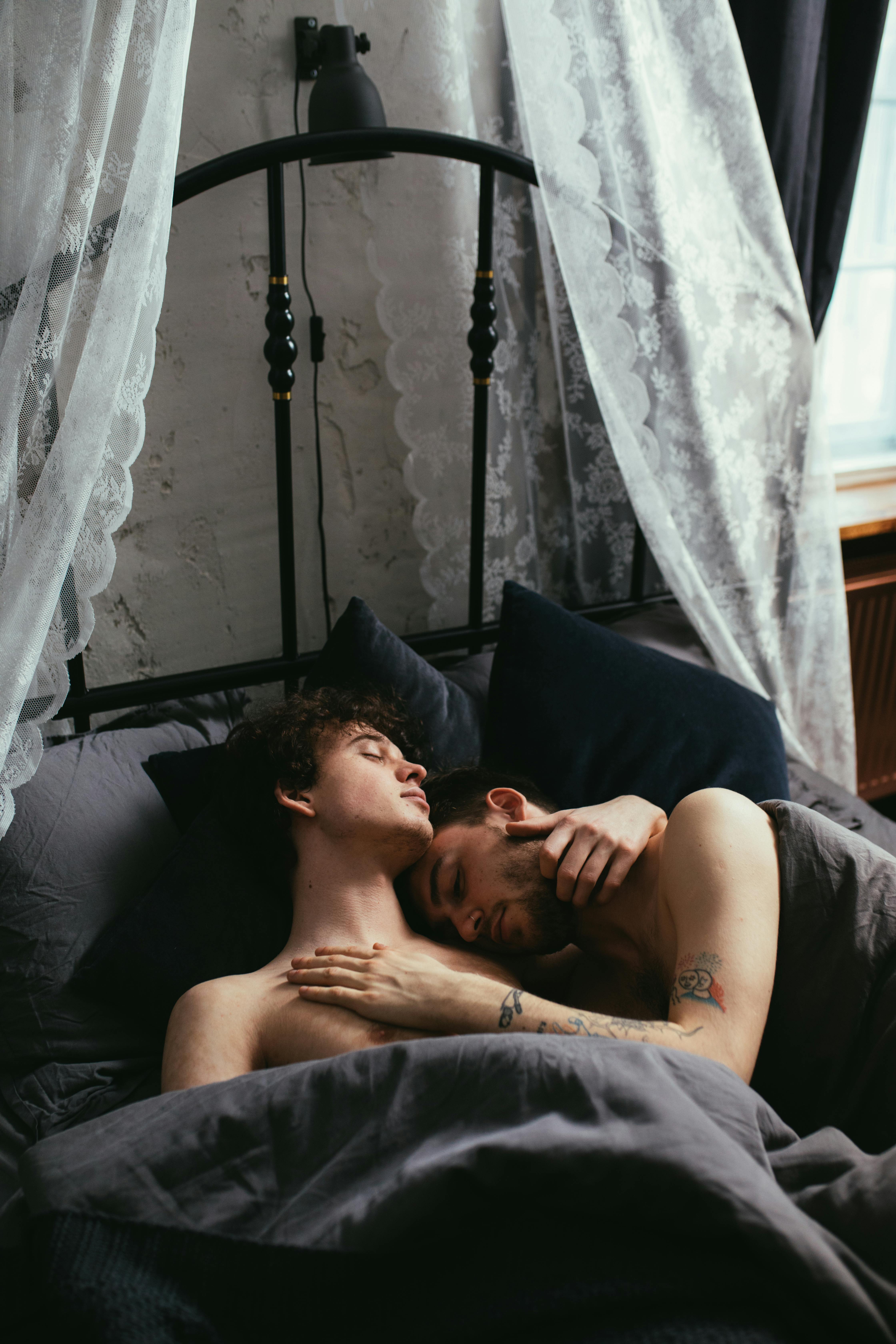 shirtless men sleeping on bed
