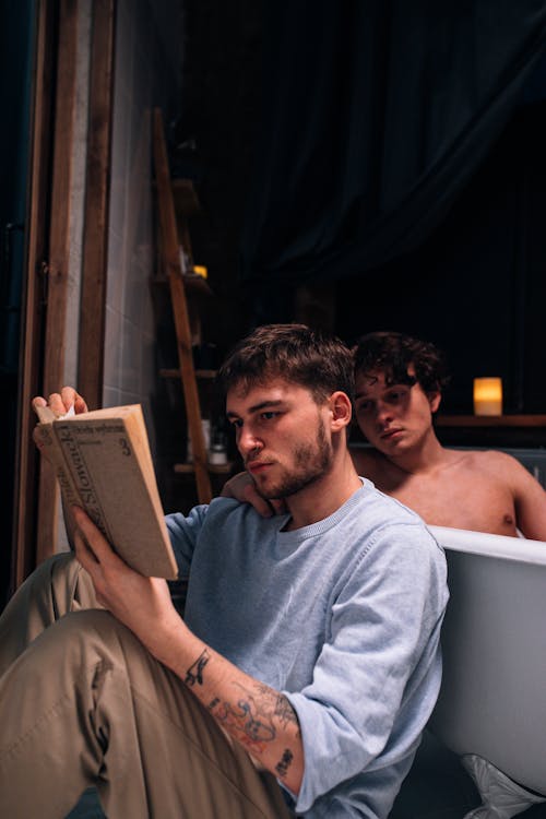 Free A Man Reading a Book Near a Man Taking a Bath Stock Photo
