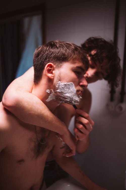 Free A couple shares an intimate moment while shaving in a bathroom. Stock Photo