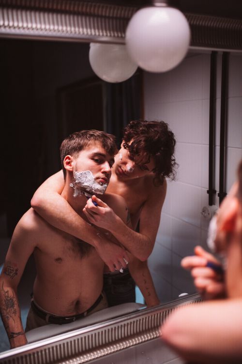 Free A romantic and intimate moment of a couple sharing grooming activities in front of a mirror. Stock Photo