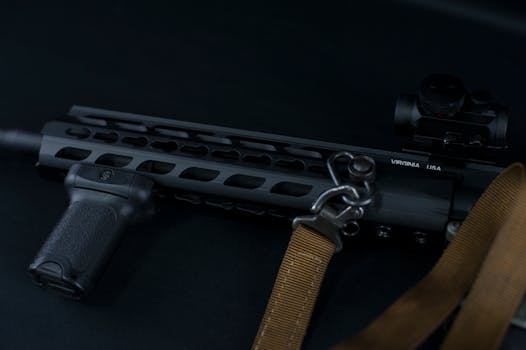 Detailed view of a tactical rifle with a sling against a dark background.