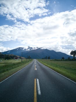 Scenic view of an empty road leading to distant mountains under a partly cloudy sky.