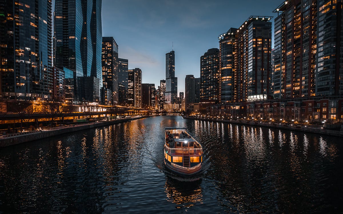 Boat on Water Near City Buildings at Night