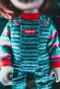 Creative design of doll in trendy overalls and striped wear in bright light on blurred background