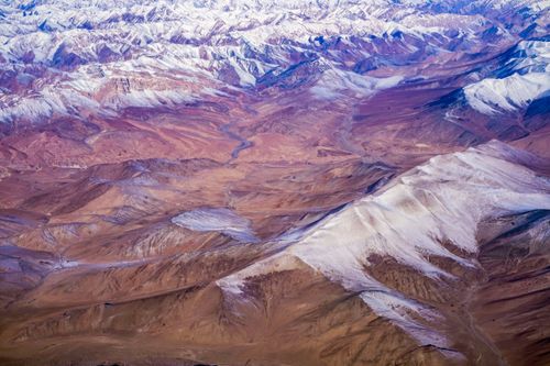 Free Spectacular aerial view of tall, snow-capped mountains contrasting with arid valleys. Stock Photo
