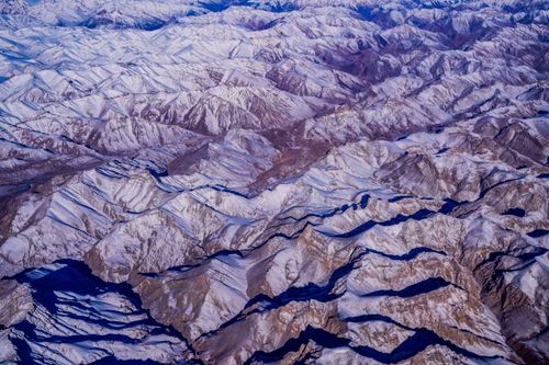 Free Breathtaking aerial view of vast snow-covered mountains in winter season. Stock Photo