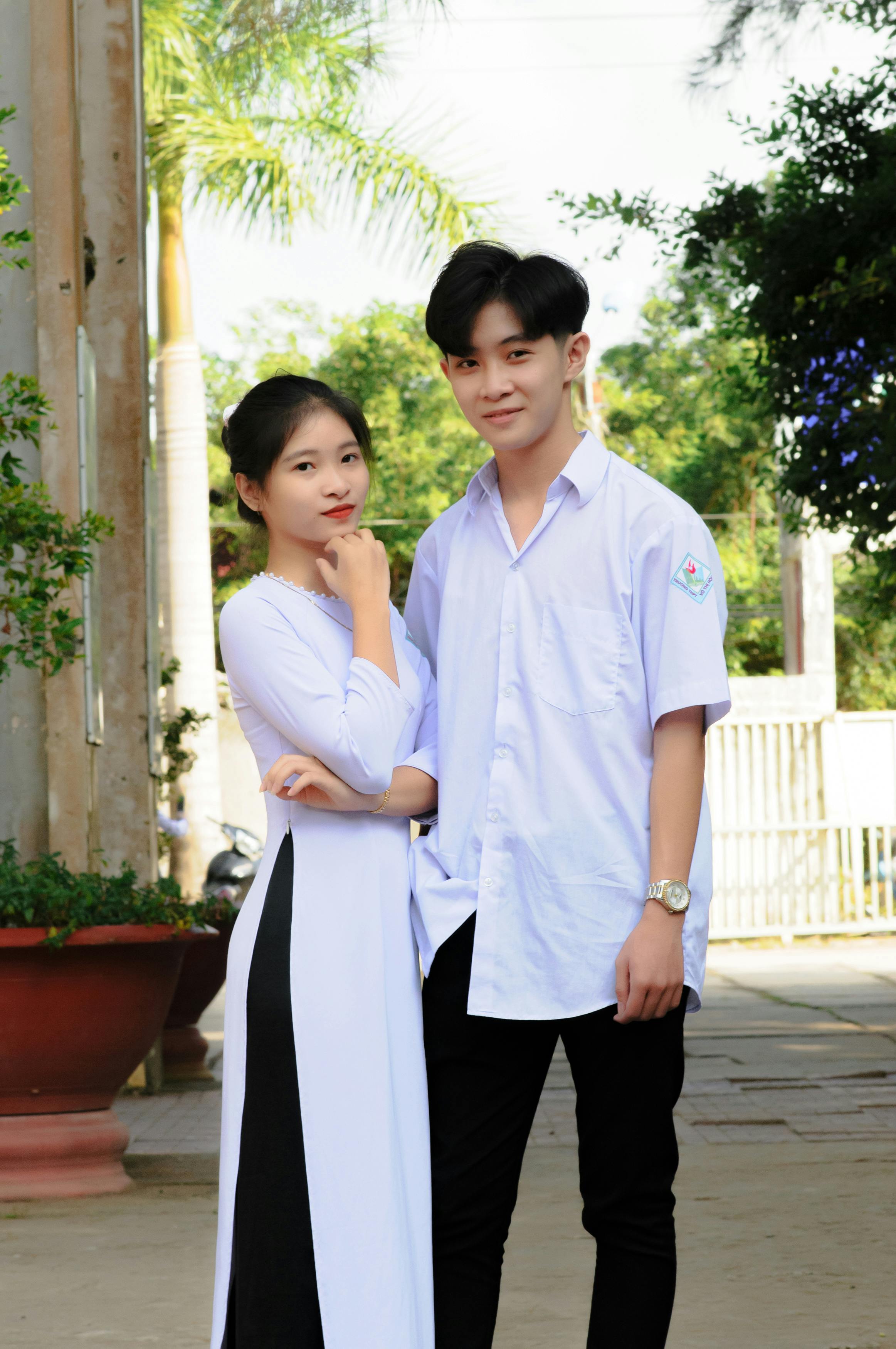 a boy in a white uniform standing beside a girl