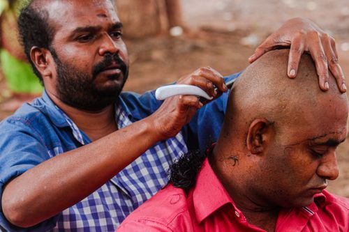 Free Close-up of a barber giving a shave outdoors in Cumbum, India, showcasing traditional grooming techniques. Stock Photo