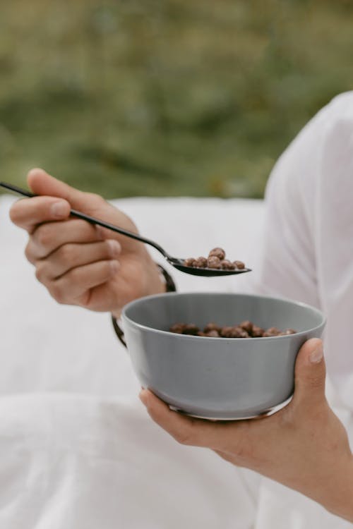 Free Selective Focus of a Person Holding a Ceramic Bowl with Chocolate Cereal Stock Photo