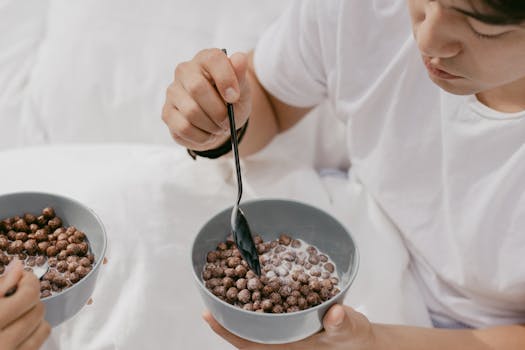 A young man enjoys chocolate cereal in a cozy indoor setting.